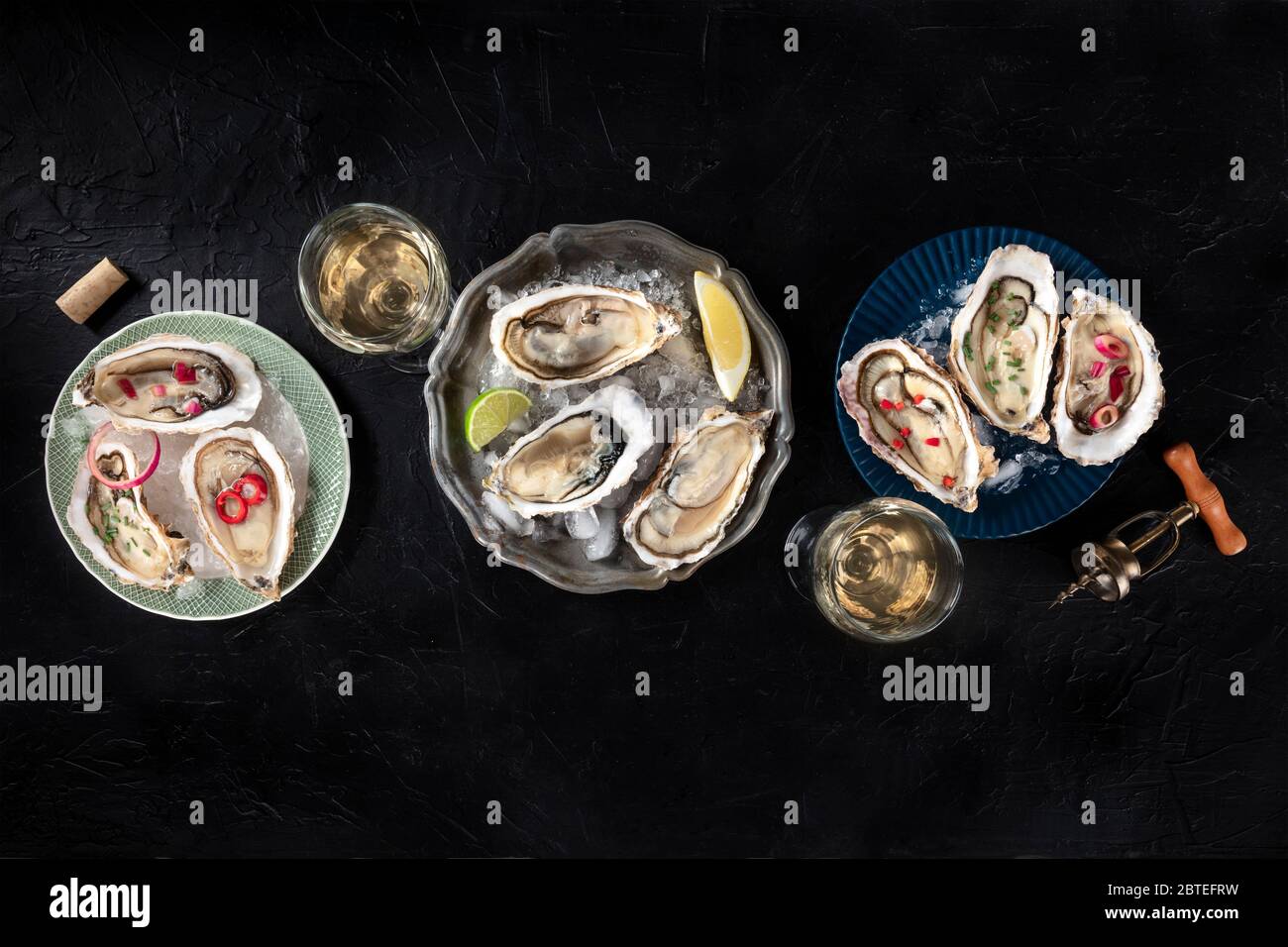 Austern mit verschiedenen Belägen, von oben geschossen, mit Zitrone und Limette, Pfeffer, Zwiebel, auf schwarzem Hintergrund mit einem Platz für Text Stockfoto