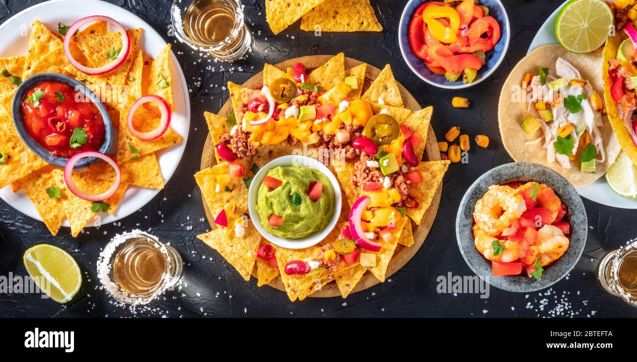 Mexikanisches Essen Panorama, Overhead-Aufnahme auf dunklem Hintergrund. Nachos, Guacamole, Tequila, Tacos, eine Flatlay Stockfoto