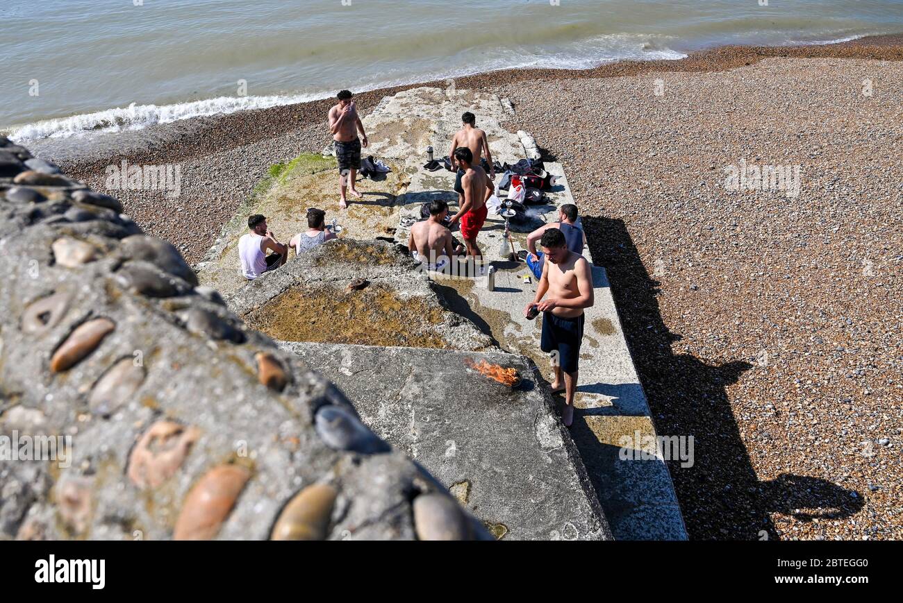 Brighton UK 25. Mai 2020 - Junge Männer feiern heute früh am Brighton Beach an einem schönen heißen sonnigen Tag. Es wird erwartet, dass Menschenmengen an schönen Orten und Stränden im ganzen Land an Feiertagen strömen, da die Temperaturen während der Coronavirus COVID-19 Pandemie-Krise im Südosten Englands die hohen 20s erreichen werden. Quelle: Simon Dack / Alamy Live News Stockfoto