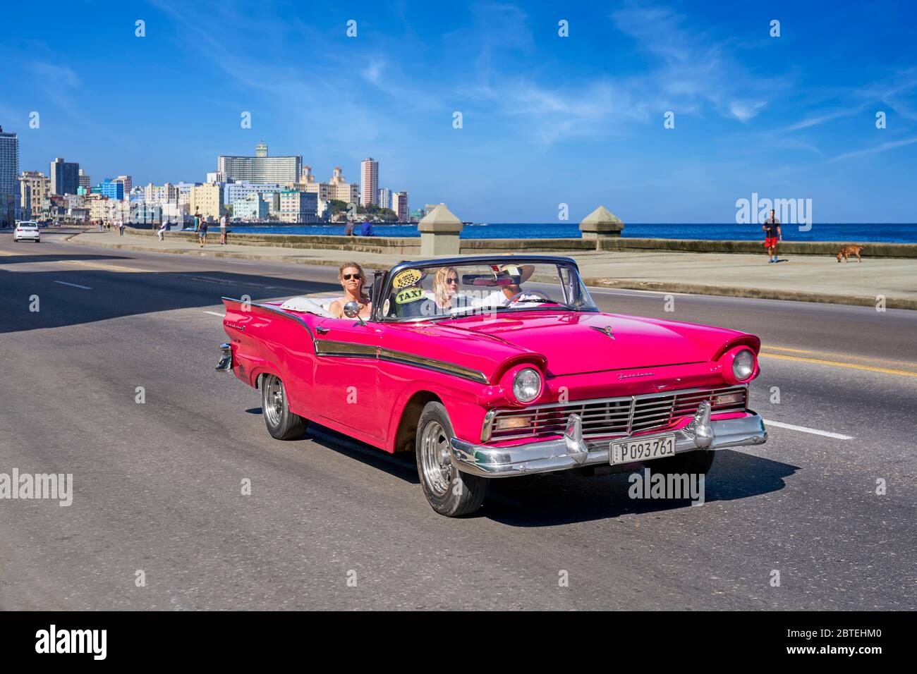 Rotes altes Auto, das entlang der Malecon, Havanna, Kuba fährt Stockfoto