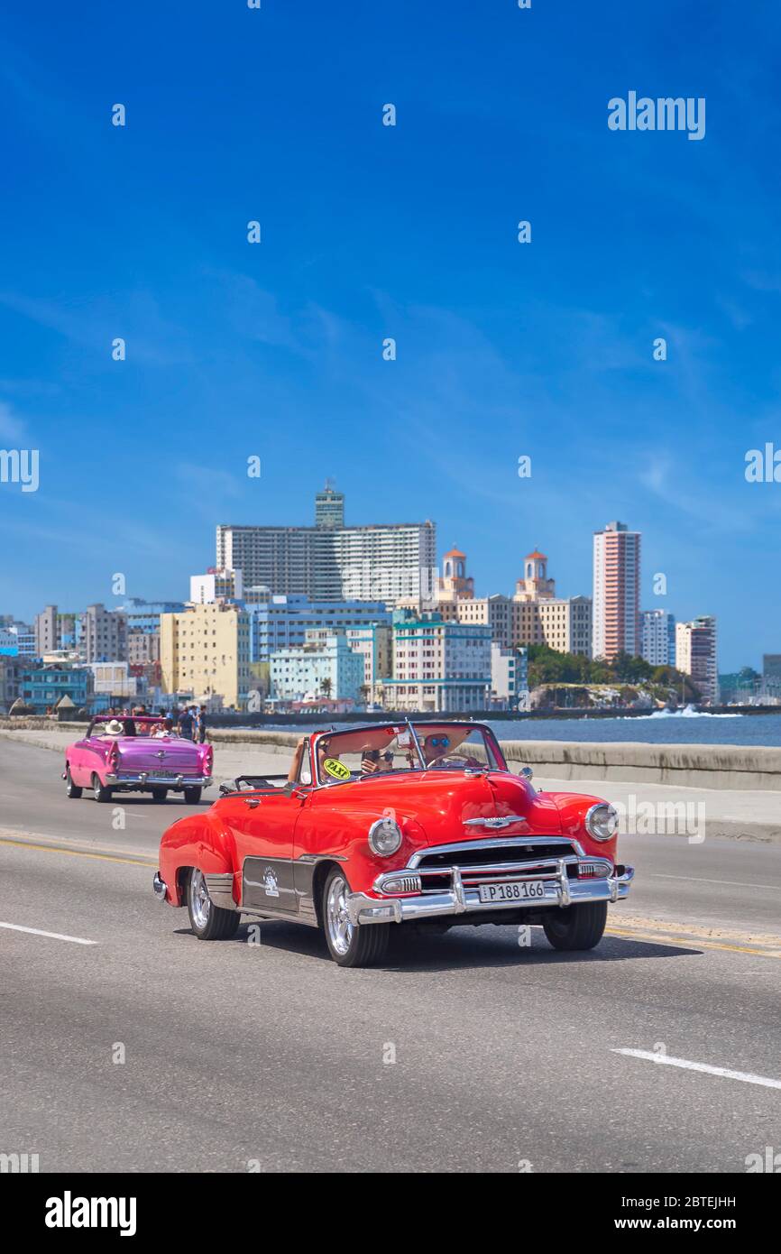 Altes rotes Auto, das entlang der Malecon, Havanna, Kuba fährt Stockfoto