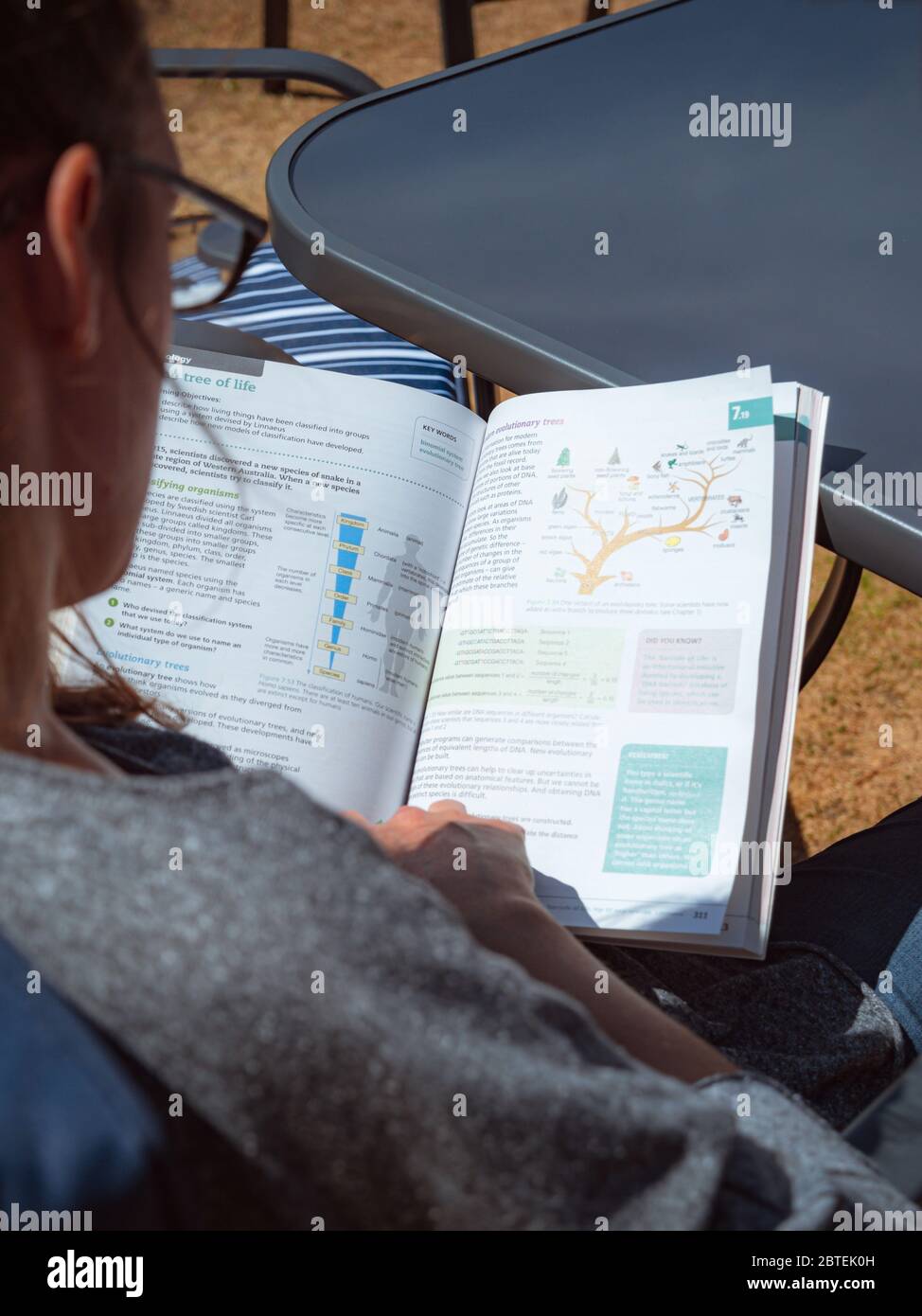 Preston, Großbritannien - Mai 28 2020: Eine junge Frau studiert ein Lehrbuch für Naturwissenschaften bei warmem Wetter in ihrem Garten Stockfoto