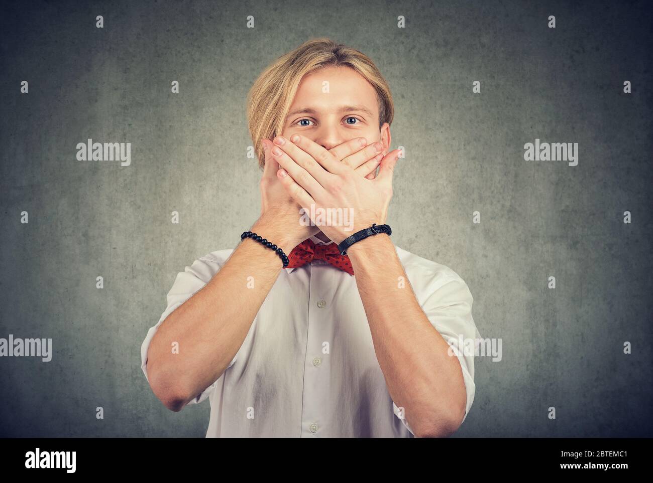 Junger Mann mit Händen über dem Mund Geste Stockfoto