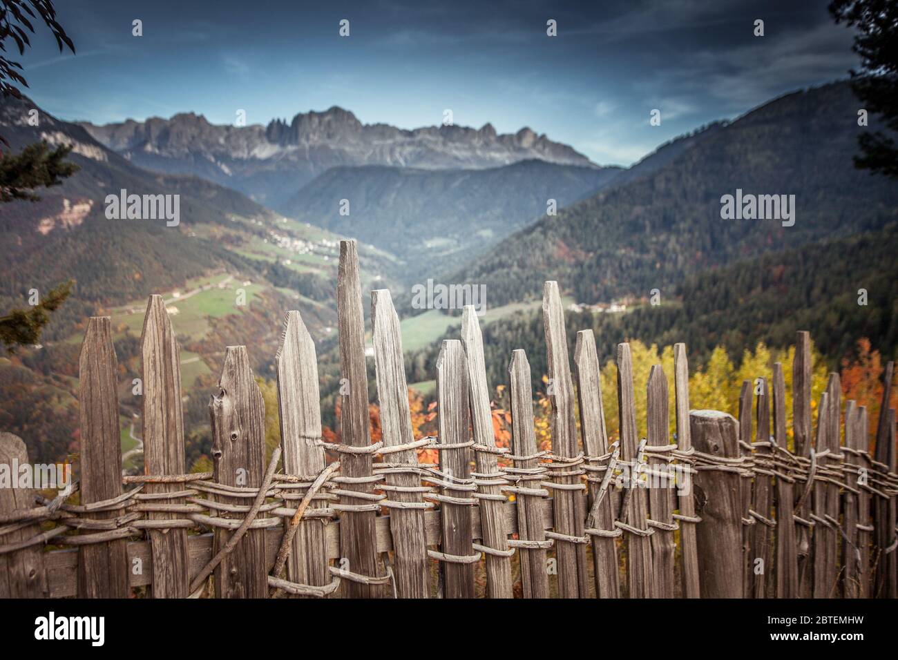 Malerischer Holzzaun mit Tyres Tal und Rosengarten Dolomit-Gipfeln im Hintergrund, Italien. Konzept: Herbstliche Dolomitenlandschaften Stockfoto