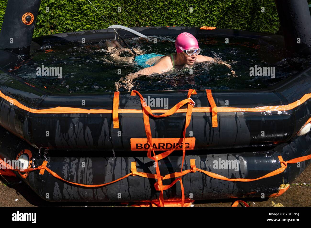 Uphall, Schottland, Großbritannien. 25 Mai 2020. Emily Aston, eine wilde Freiwasser-Schwimmerin mit der Gruppe der Fufe Wild Schwimmer, während eines täglichen Tauchens in ihrem Gartenpool, der aus einem Schiffsfloß gemacht wurde. Vielen Wildschwimpern wurde die Möglichkeit verwehrt, während der Sperrung von Covid-19 ihren Sport zu treiben, und sie haben Pools für ihre Gärten gekauft, um ihr Wohlbefinden zu erhalten. Iain Masterton/Alamy Live News Stockfoto