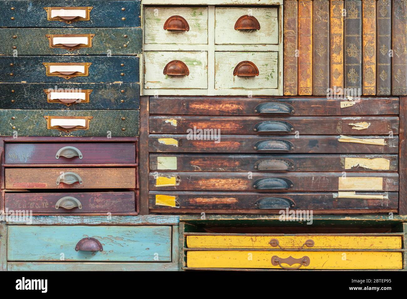 Bunte Auswahl an Vintage Holzschubladen und Bücher mit Etiketten und Griffen Stockfoto
