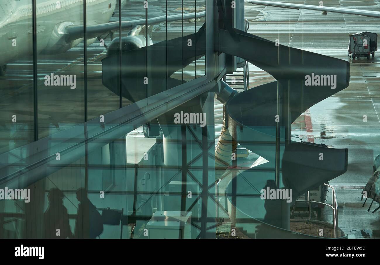 Flughafen in Brüssel vom Fenster aus die teilweise Spiegelung eines Flugzeugs, die Spiegelung aus dem Inneren der Flughafenhalle mit wenigen Silhouetten Stockfoto