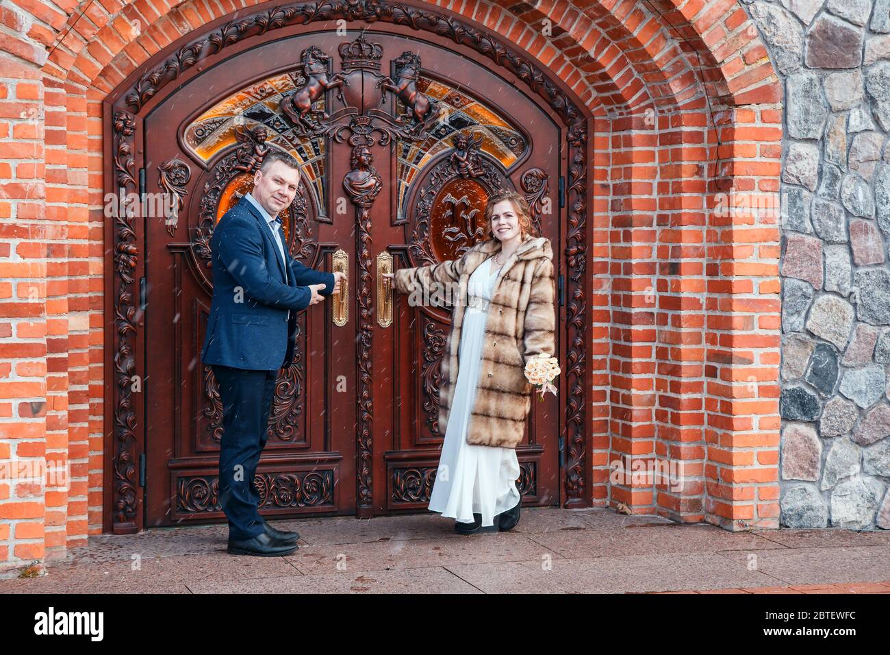 Frisch verheiratetes Paar, das am frühen Frühlingstag in der Nähe der Burgtür im Stadtpark steht Stockfoto