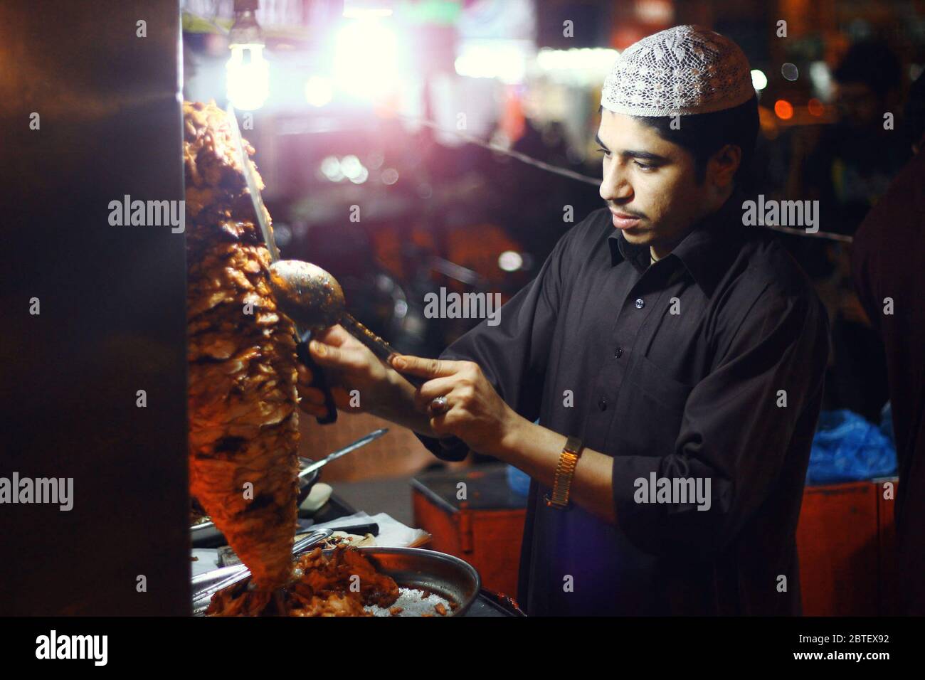 Junger Mann, der Shawarma in Bahadurabad, Karachi, Pakistan schlägt 13/03/2013 Stockfoto