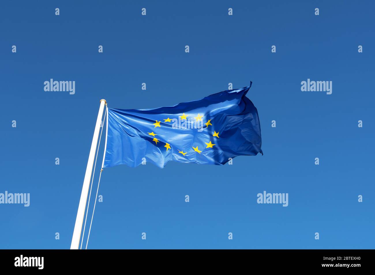 EU-Flagge - blaue Leinwand mit gelben Sternen wehen in blauen klaren Himmel Stockfoto