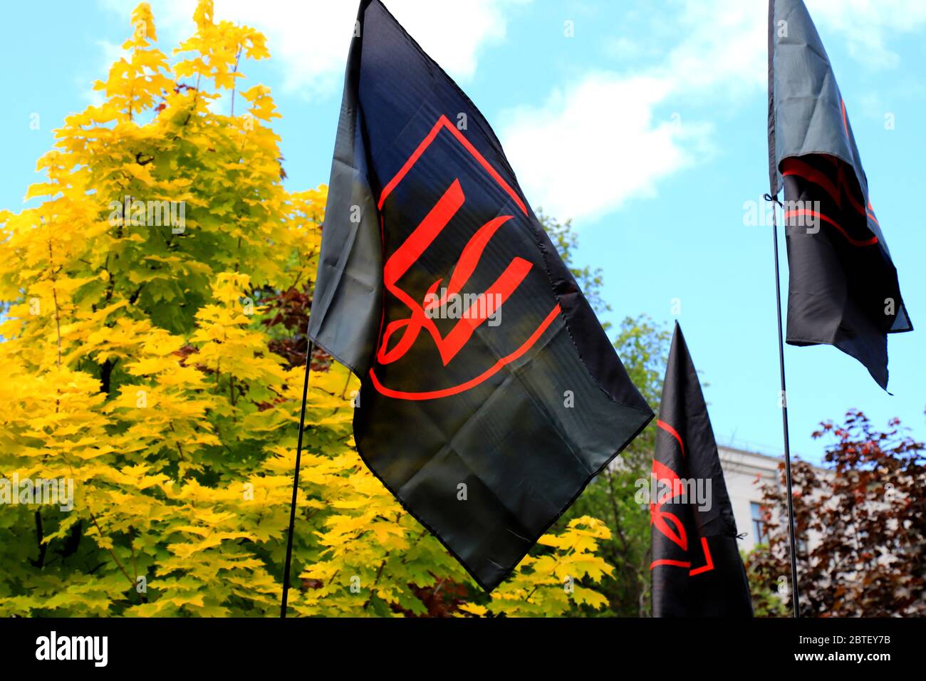 Eine rote schwarze patriotische ukrainische Flagge mit einem roten Wappen der Ukraine fliegt während einer Demonstration in Dnipro. Nationales Symbol, Widerstandsflagge. Stockfoto