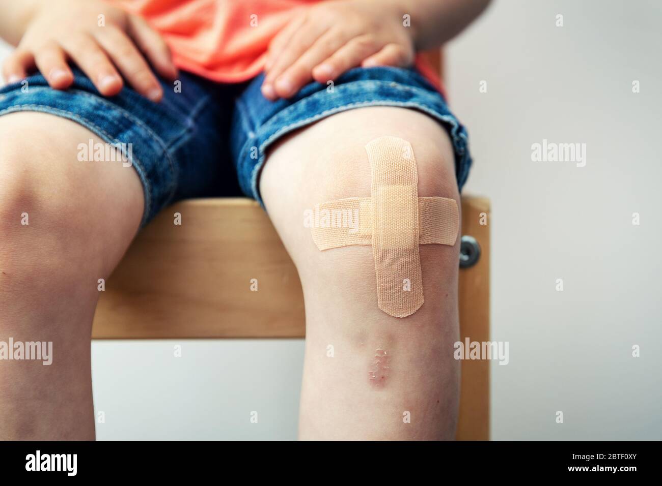 Kinderknie mit Klebebandage und Bluterguss Stockfoto