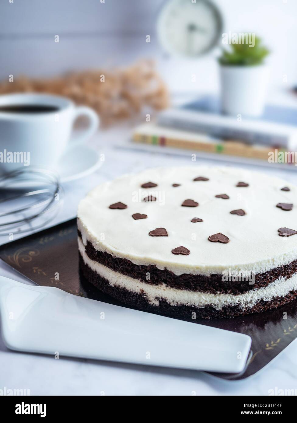 Weiße Schokolade Schicht Kuchen , mit Ei Schneebesen , Kaffeetasse und Bouquet von Blumen, selektive Fokus dekoriert. Frische hausgemachte Bäckerei Konzept Stockfoto