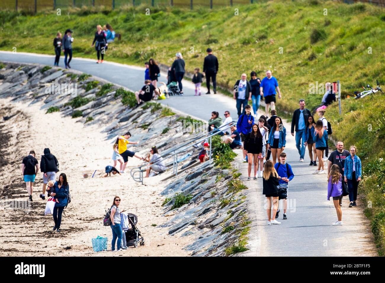 Menschenmassen versammeln sich am Strand und entlang des Fußweges Helen's Bay in Co. Down on the Bank Holiday. Stockfoto