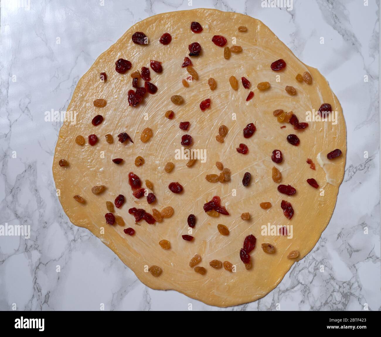 Prozess der Zubereitung von Osterkuchen Cruffin, mit getrockneten Früchten und Nüssen dekoriert. Stockfoto