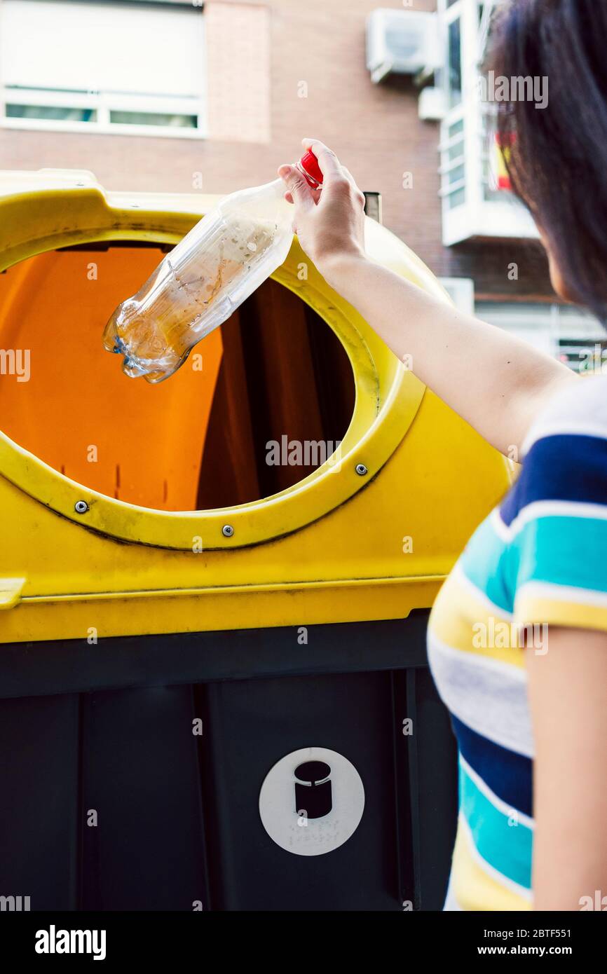 Frau wirft Flasche in Recycling-Behälter. Recyclingkonzept. Stockfoto