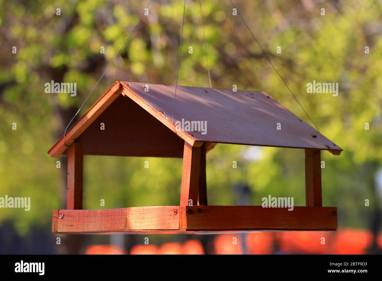 Vogelhaus aus Holz, Krippe, die in einem Frühlingspark an einem Baum hängt. Wildvogelpflege, Zuhause und Nahrung. Vogelnest im Frühling Stockfoto