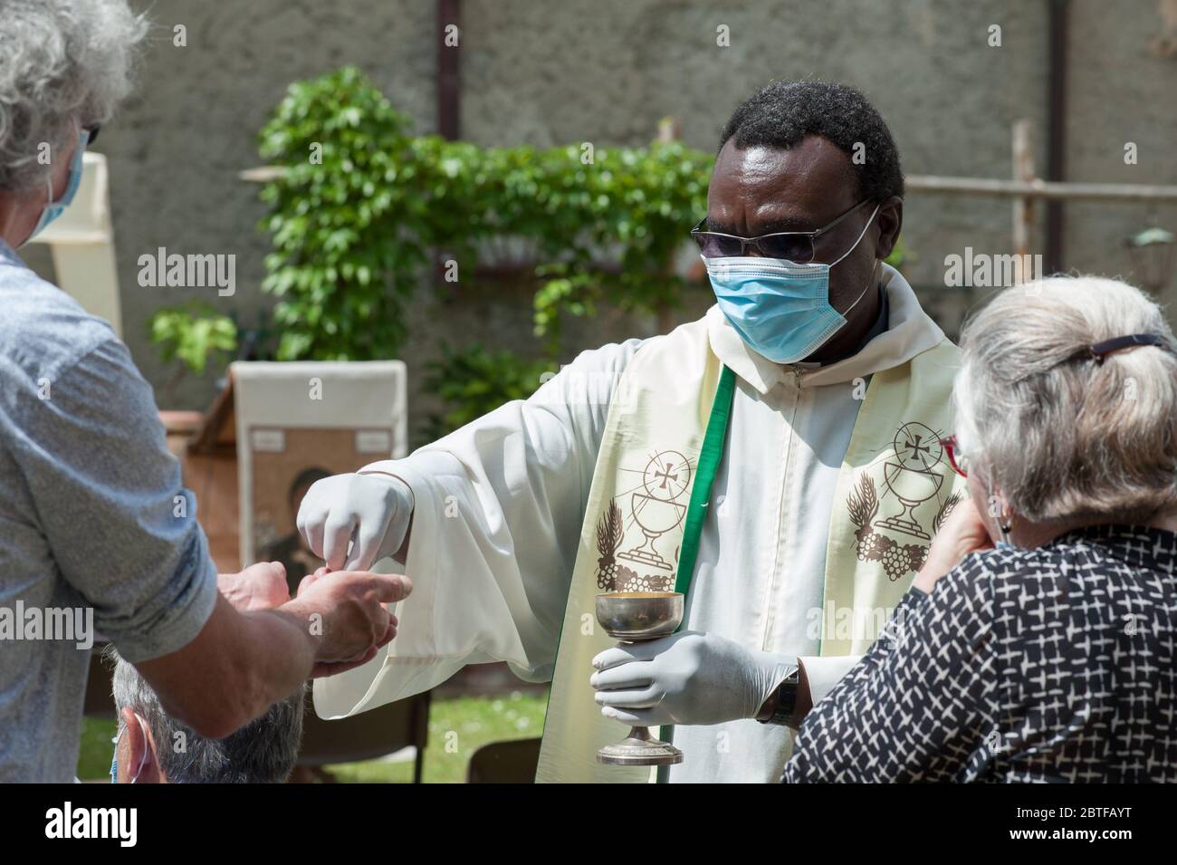 Italien - 2020. Mai 24: Der Priester feiert die Messe während der Blockade des Covid-19. Die Gläubigen empfangen die Heilige Hostie mit Handschuhen und Schutzmasken. Stockfoto