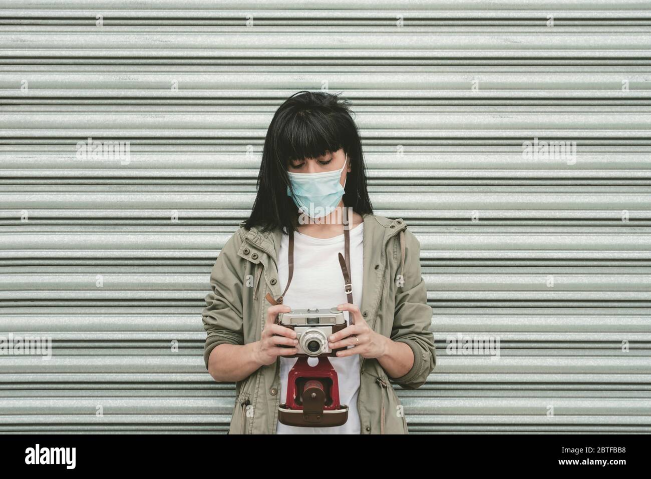 Frau trägt medizinische Maske nehmen Sie Fotos mit seiner Kamera im Freien Stockfoto