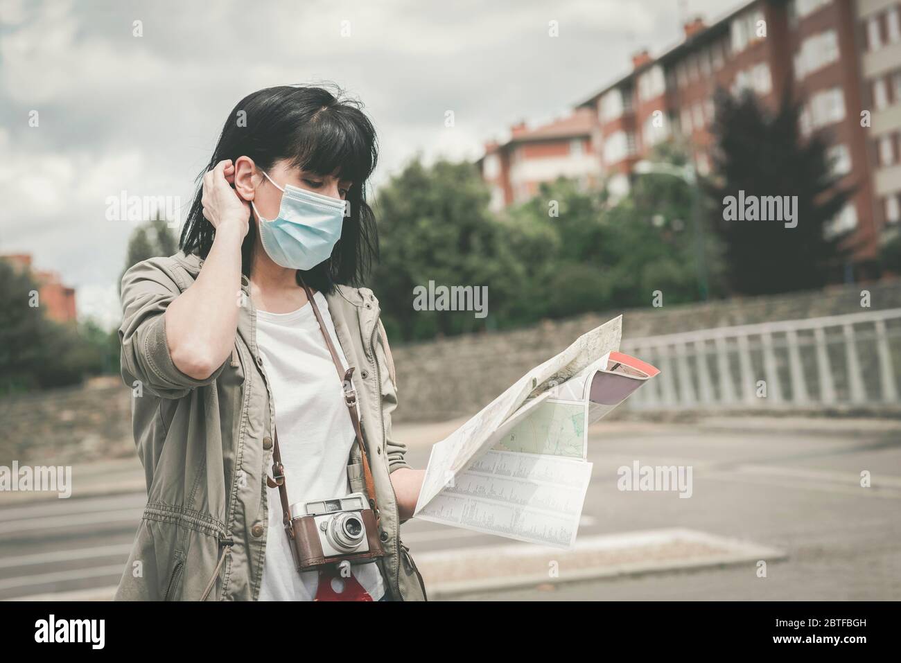 Frau mit medizinischer Maske mit Kamera Blick auf eine Karte der Stadt im Freien Stockfoto