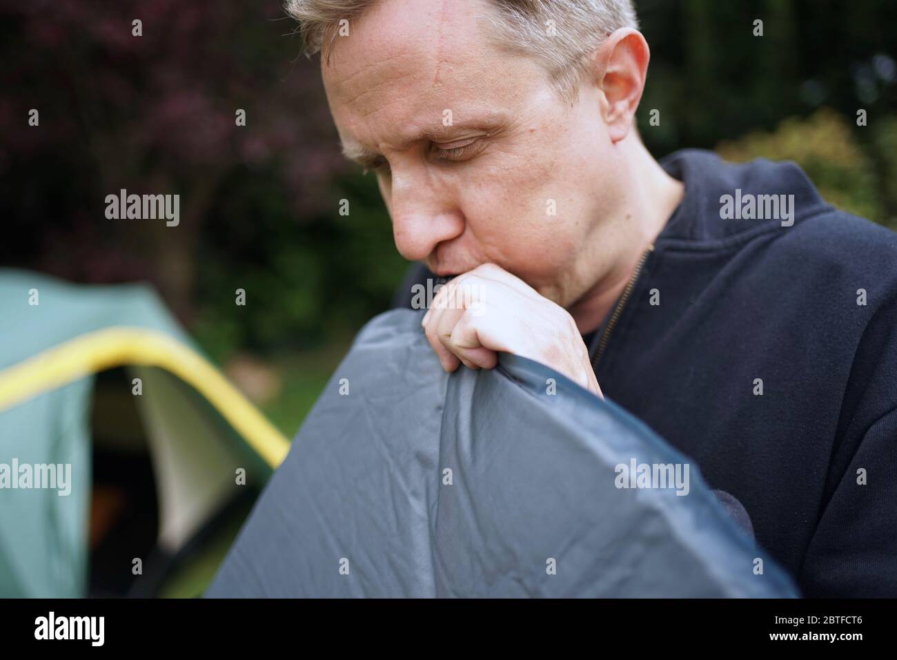Nahaufnahme von Mann bläst ein selbst aufblasbare Schlafpolster für Camping Stockfoto