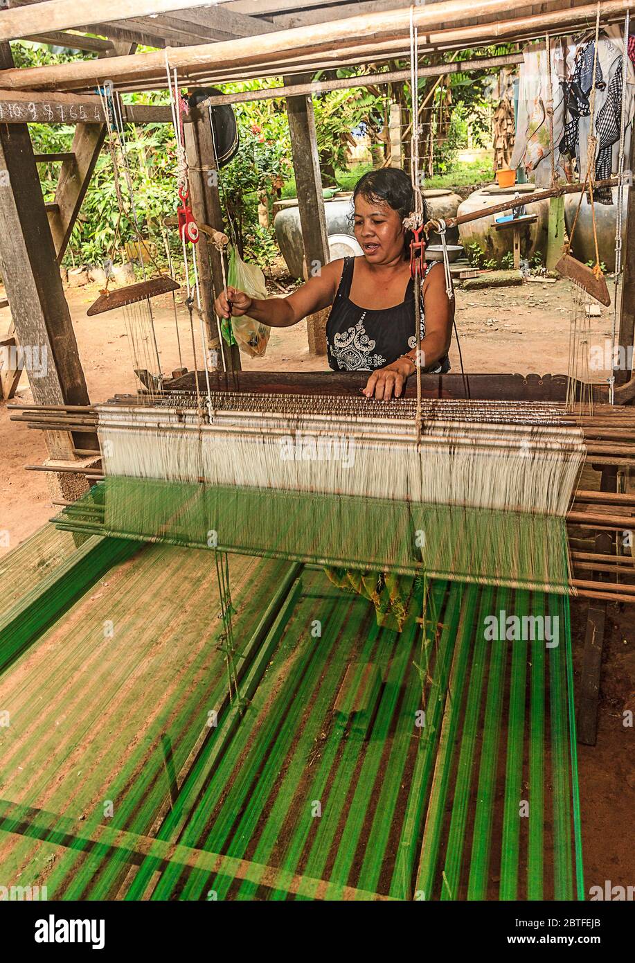 Seidenweberei auf Koh Dach Island, einer Insel vor dem Zentrum von Phnom Penh, Kambodscha. Hier webt eine Frau Seidenstoff von Hand auf einem Webstuhl unter ihrem Haus. Stockfoto