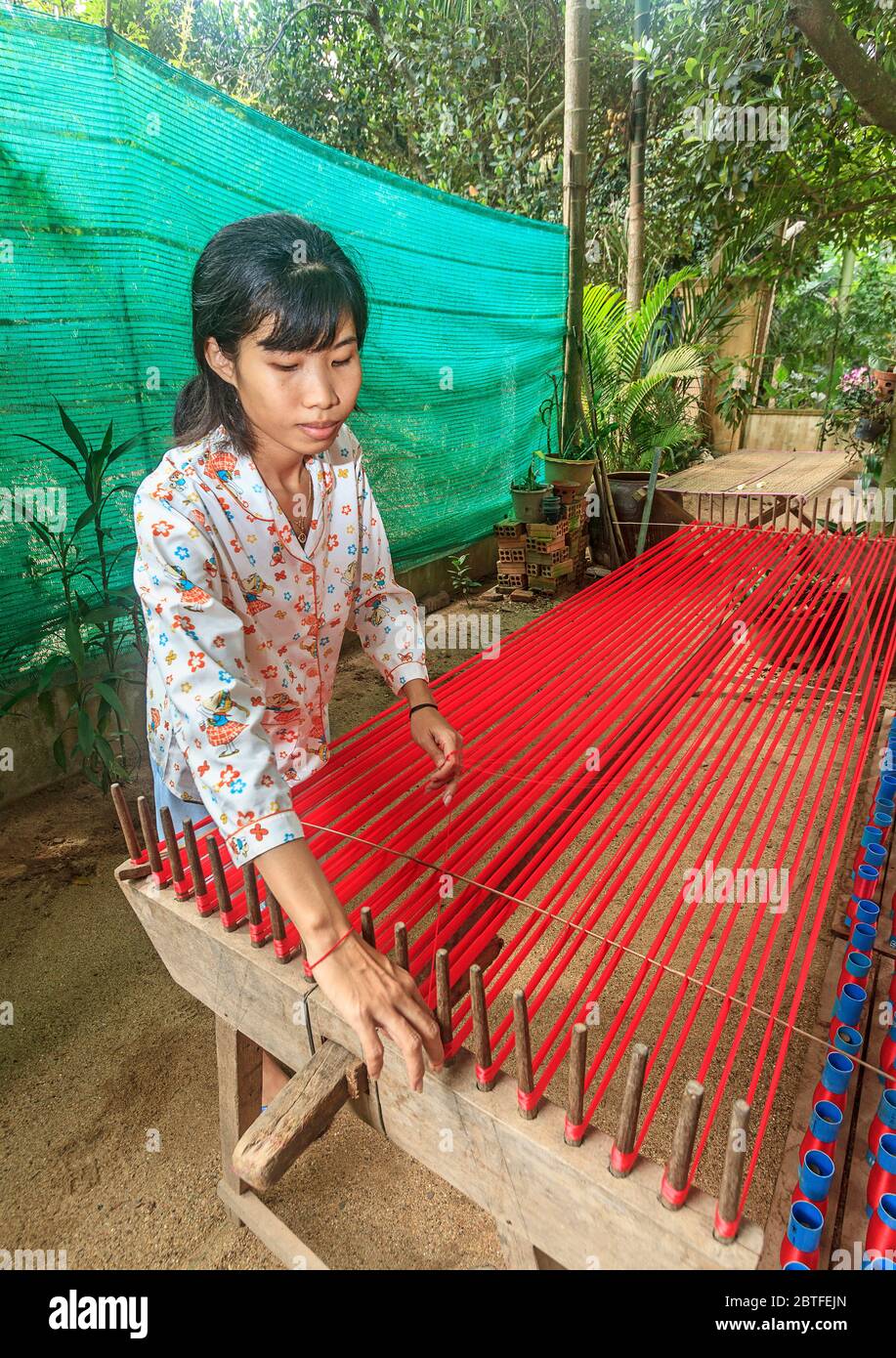 Seidenweberei auf Koh Dach Island, einer Insel vor dem Zentrum von Phnom Penh, Kambodscha. Hier nimmt eine Frau Seidenfäden von Spulen und richtet sie gerade Stockfoto