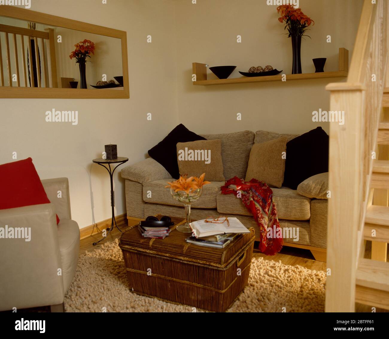 Beiges Velours-Sofa und Vintage-Brust in gemütlicher Ecke neben der Treppe Stockfoto