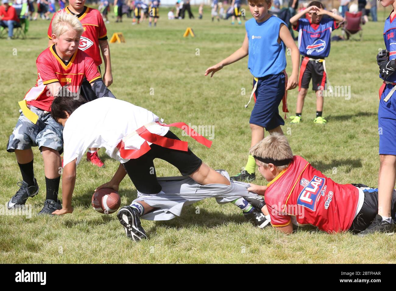 Jugend Flagge Fußball Spiel Action Schuss defensiven Spieler ziehen die Shorts des Ballträgers statt ziehen seine Gegner Flagge. Stockfoto