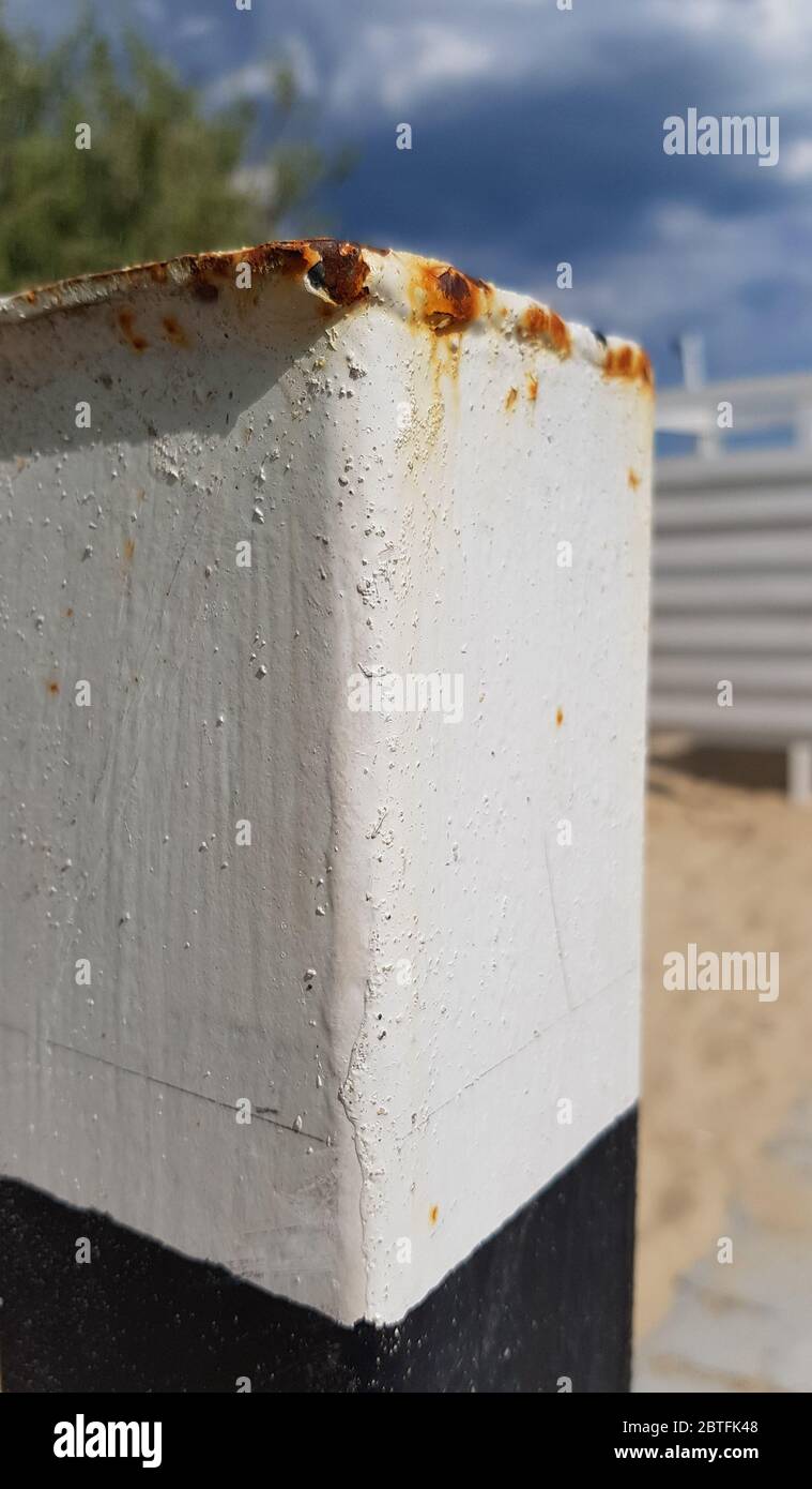 Alte rostige Metallsäule in weißen und schwarzen Farben lackiert. Weiß lackierte Metallic-Oberfläche mit rostigen Tropfen und Flecken Nahaufnahme Stockfoto