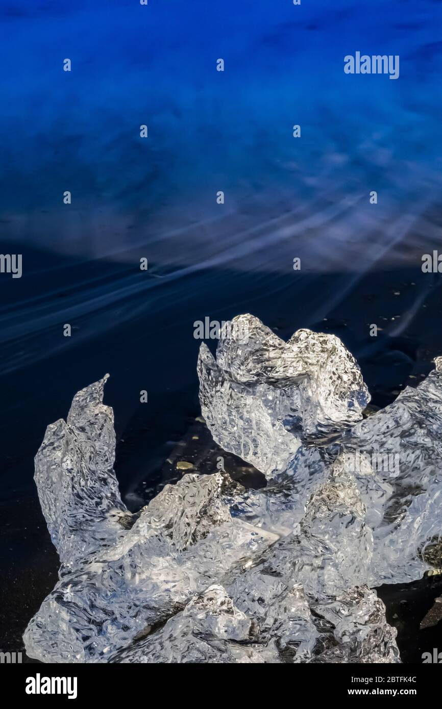 Schmelzender Klumpen klaren Eiseises, ursprünglich vom Breiðamerkurjökull Gletscher in die Lagune von Jökulsárlón eingekalbt, am Diamond Beach an der Südküste Stockfoto