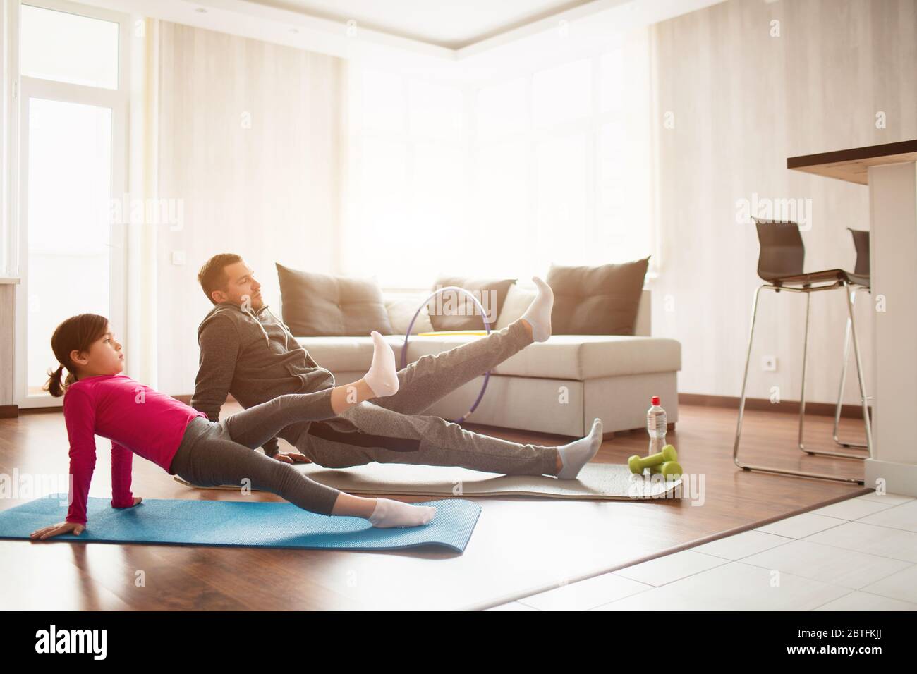 Vater und Tochter trainieren zu Hause. Training in der Wohnung. Sport zu Hause. Reverce Plank mit Bein heben auf dem Boden zu Hause. Stockfoto