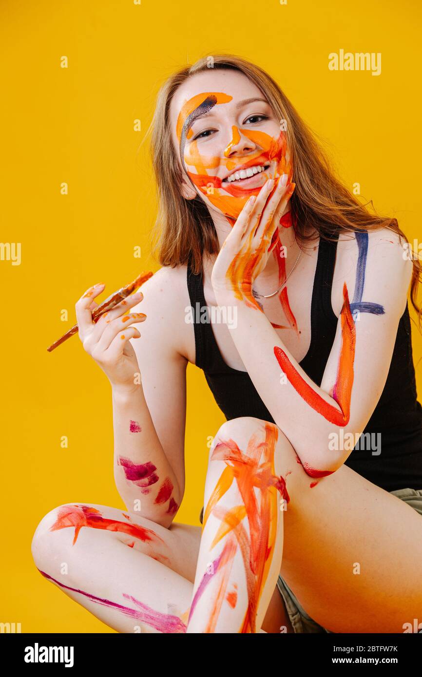 Verspielt zwanzig Jahre altes Mädchen lächelt vor der Kamera, sie zufällig malte ihren Körper Stockfoto