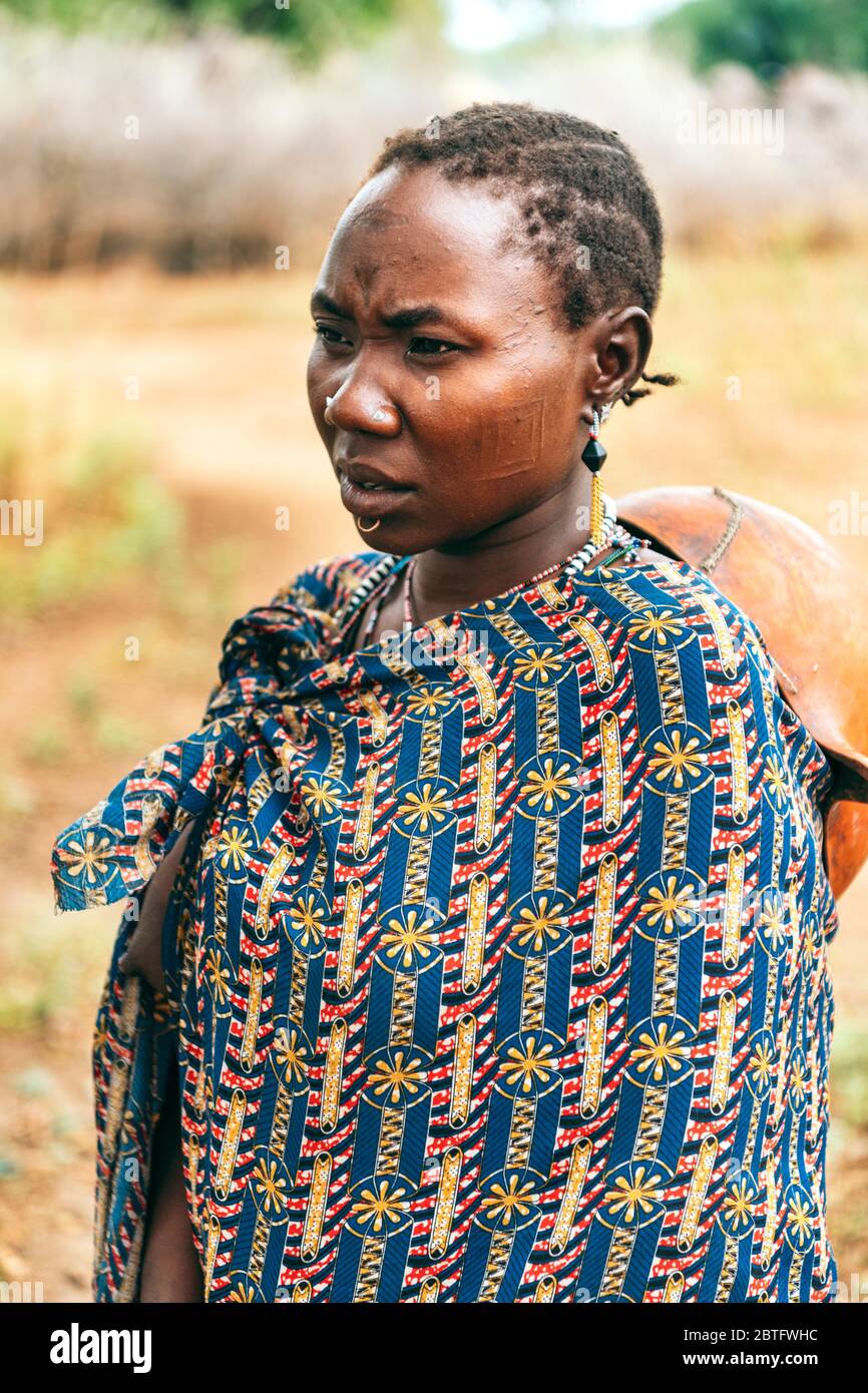 TOPOSA STAMM, SÜDSUDAN - 12. MÄRZ 2020: Frau in bunte Ziergewand gehüllt, wegblickend auf dem Feld in der Nähe von Toposa Stamm Stockfoto