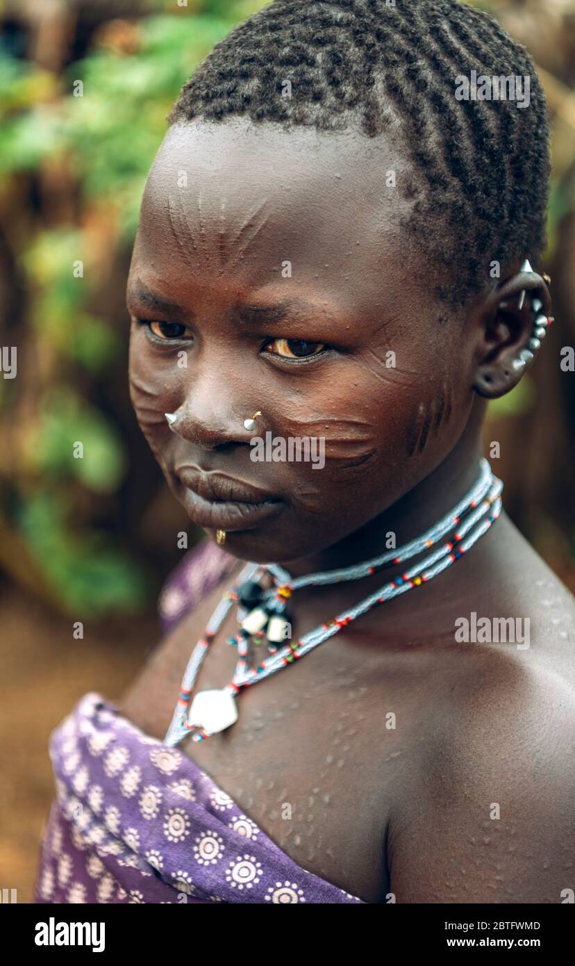 TOPOSA TRIBE, SÜDSUDAN - 12. MÄRZ 2020: Mädchen mit Narbengesicht und traditionellen Accessoires, die im Dorf Toposa leben Stockfoto