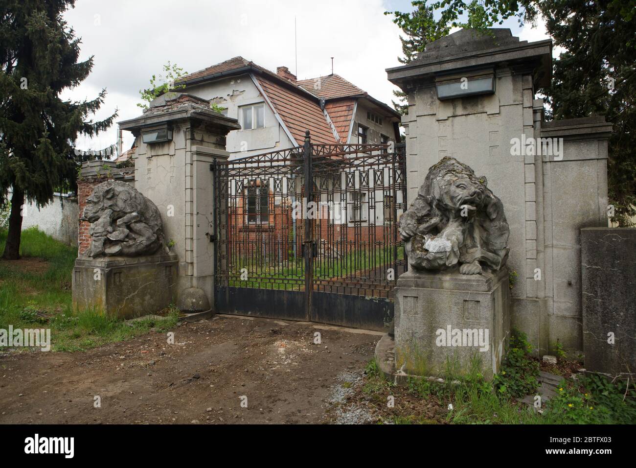 Verlassene Tor des Unteren Palastes (Dolní zámek) in Panenské Břežany in Mittelböhmen, Tschechische Republik. Das Schloss gehörte dem jüdischen Zuckerproduzenten Ferdinand Bloch-Bauer und seiner Frau Adele Bloch-Bauer, die als Vorbild für das berühmte Porträt des österreichischen Malers Gustav Klimt bekannt war. Während der Nazi-Besetzung diente der Palast als Residenz für Reinhard Heydrich, der stellvertretender Beschützer von Böhmen und Mähren war. Am 27. Mai 1942 ging er durch dieses Tor zu Beginn seiner berüchtigten Reise nach Prag, wo er von tschechoslowakischen Soldaten als Folge der Operation Anthropoid schwer verletzt wurde. Stockfoto