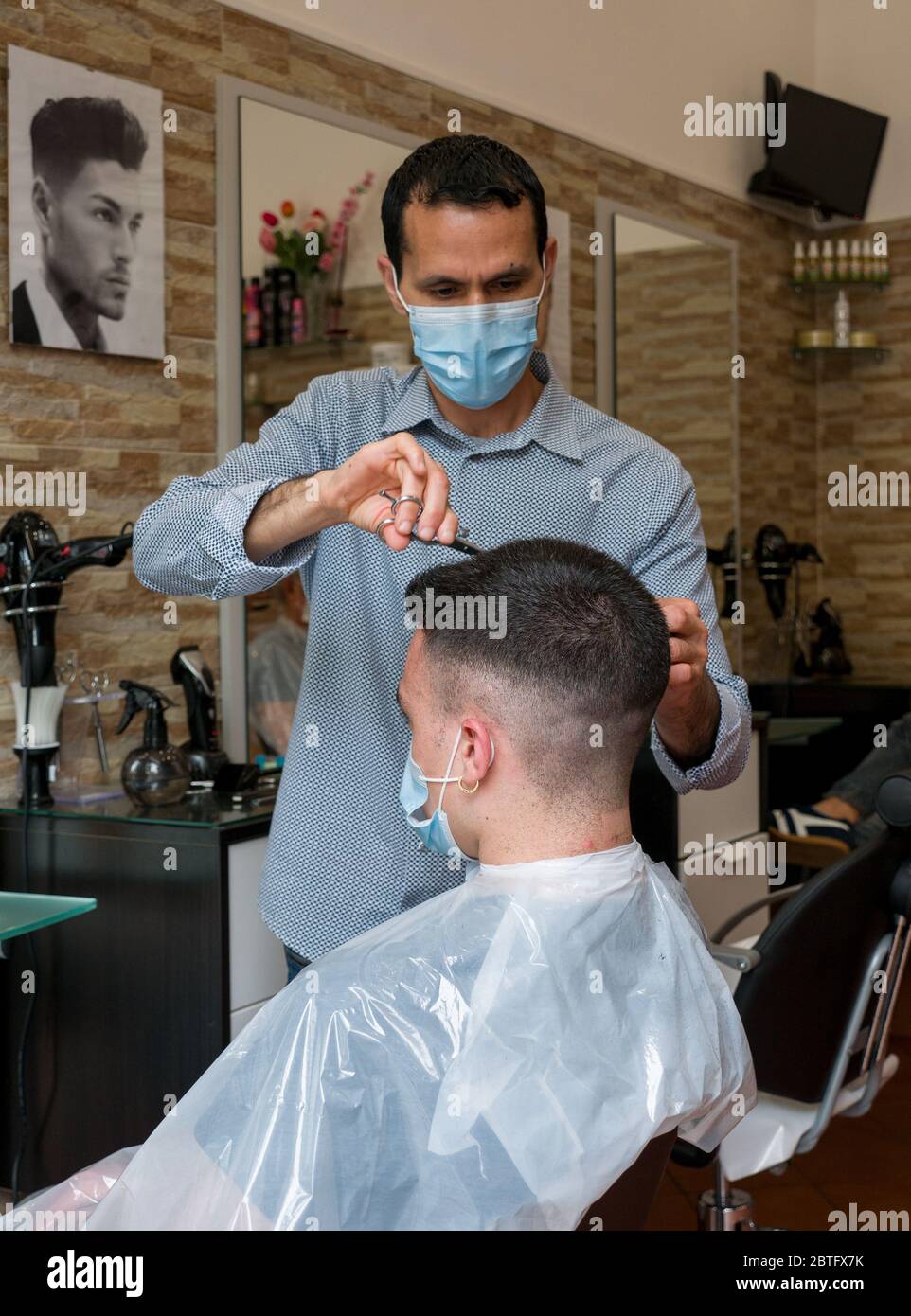 Florence, Italien - 2020, Mai 18: Junge im Friseurladen erhalten einen Haarschnitt mit Schutzmaske, während Covid-19 Sperrung. Stockfoto