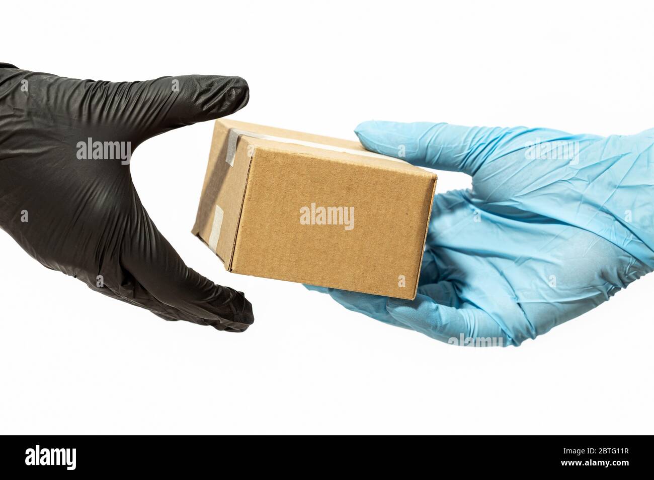 Kurier Mann Hand in schützenden Handschuh liefert ein Paket an einen Kunden oder Online-Käufer. Lieferung nach Hause während der COVID-19-Pandemie des Coronavirus Stockfoto