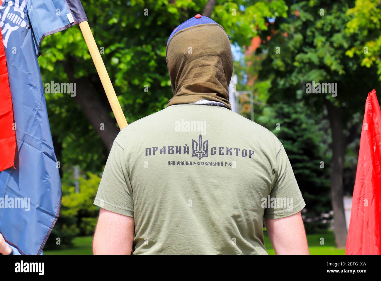 Ein Mann in T-Shirt mit Inschrift in Ukrainisch - der richtige Sektor und Wappen der Ukraine steht bei der Kundgebung mit Flagge. Patriotisches nationales Symbol. Stockfoto