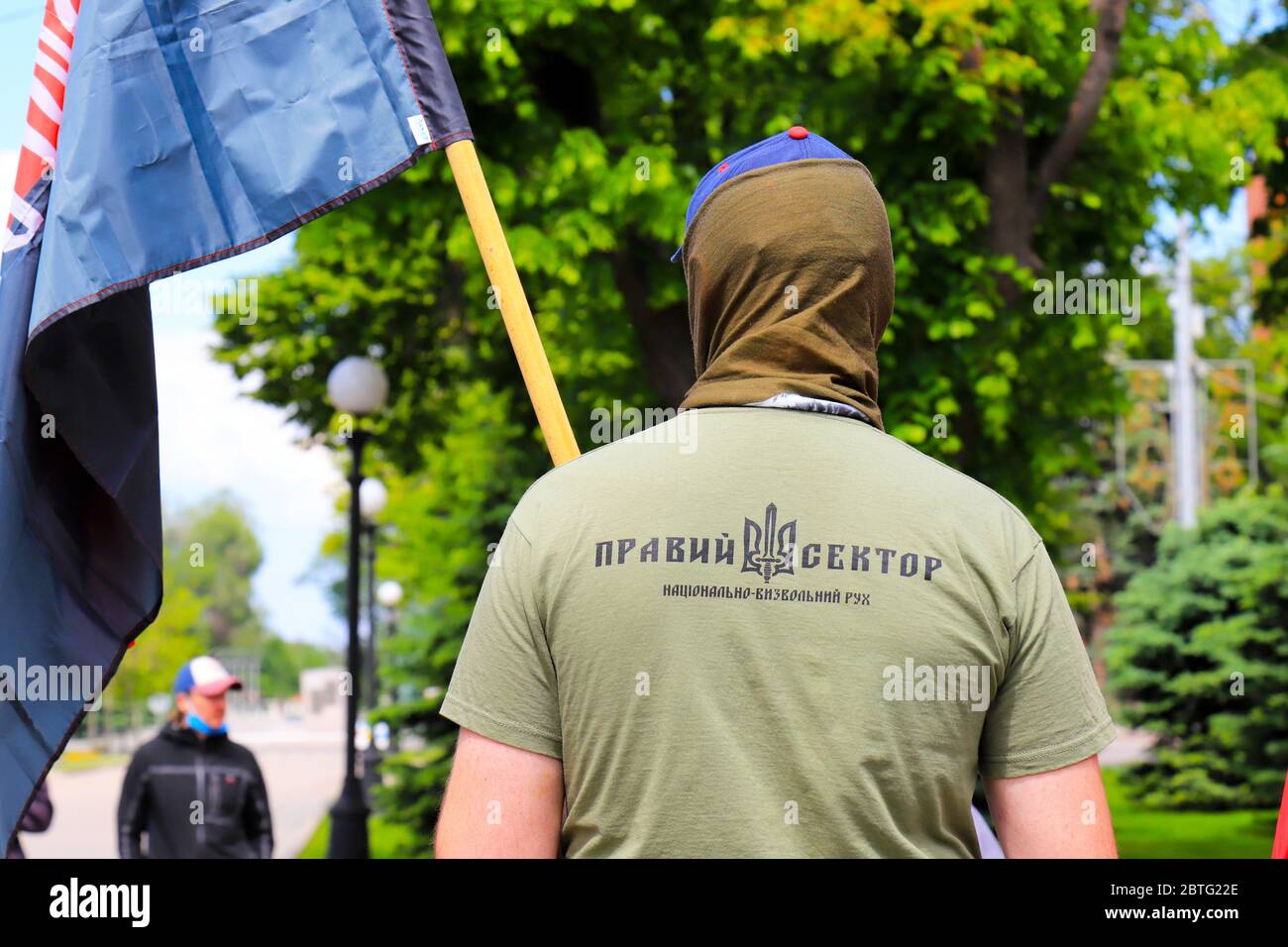 Ein Mann in T-Shirt mit Inschrift in Ukrainisch - der richtige Sektor und Wappen der Ukraine steht bei der Kundgebung mit Flagge. Patriotisches nationales Symbol. Stockfoto