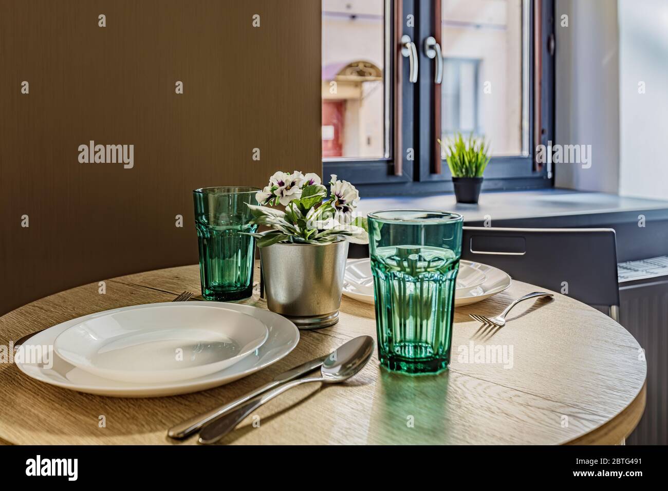 Nahaufnahme eines kleinen Couchtisches mit Tellern, die neben dem Fenster im Zimmer stehen Stockfoto