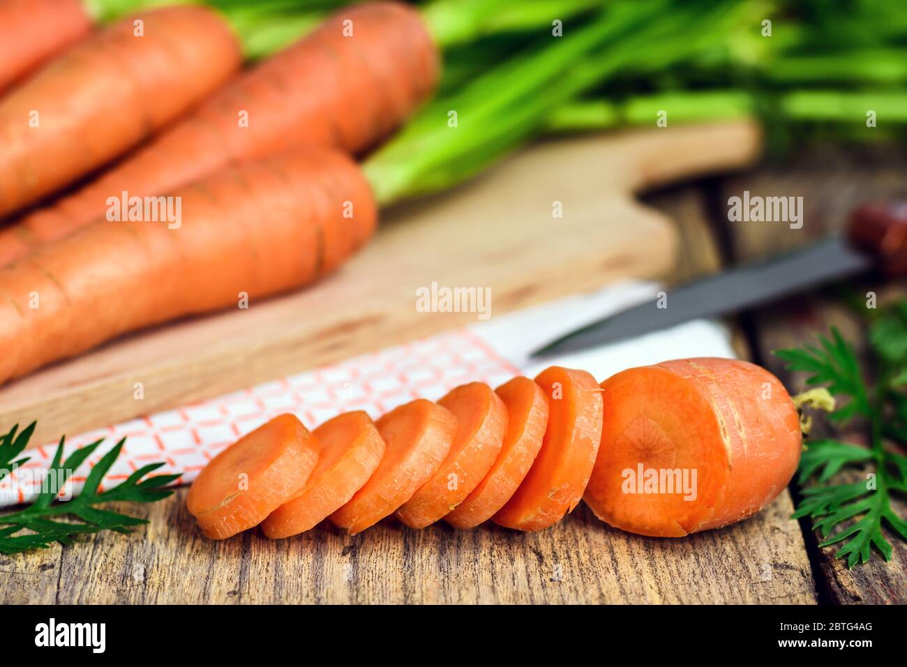 Frisch geschnittene Karotten auf einer Holzschultafel mit Messer, Geschirrtuch und Schneidebrett. Selektiver Fokus. Stockfoto