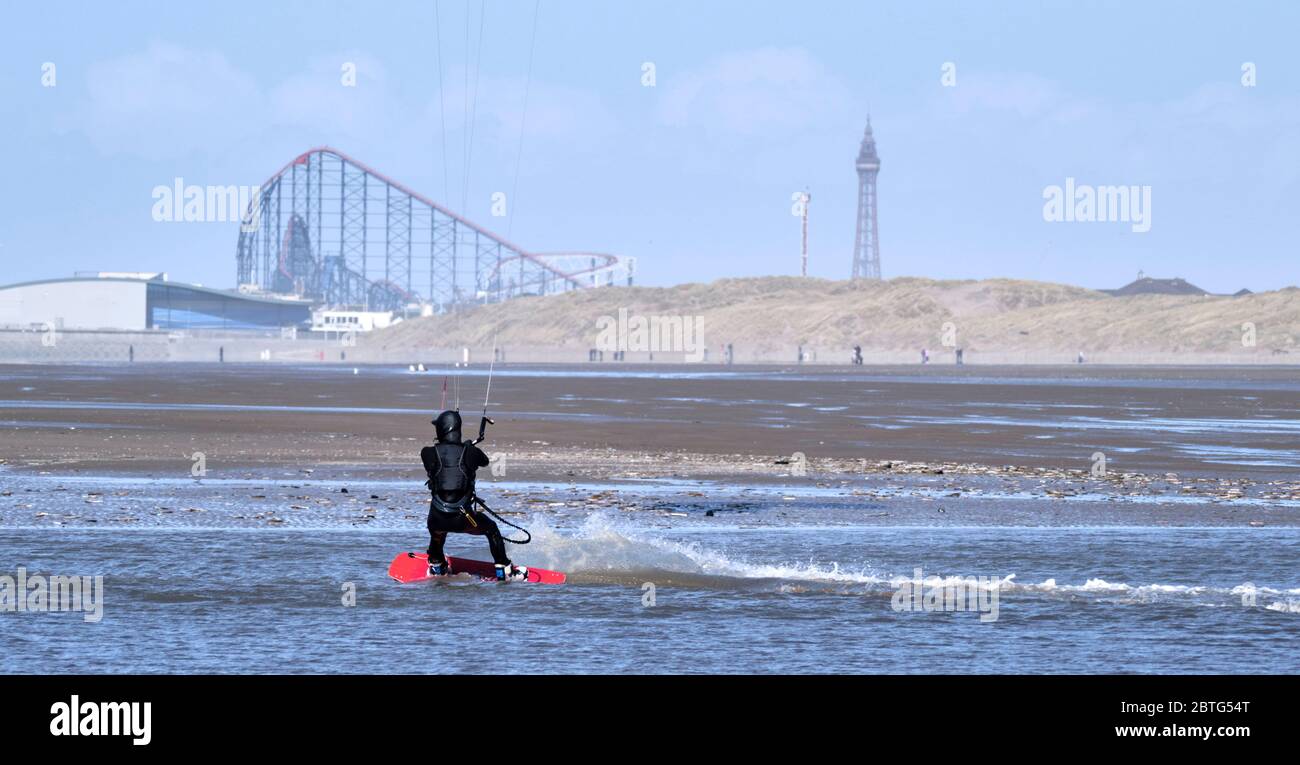 Ein Kitesurfer, Wellenreiten mit einer Achterbahn und Blackpool Tower im Hintergrund an einem Küstengebiet. Stockfoto