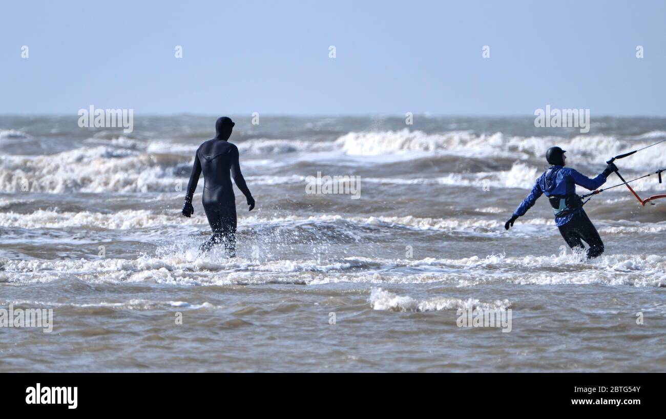 Zwei Personen in Neoprenanzügen mit Surfbrett, die Wassersport im rauen Meer genießen Stockfoto