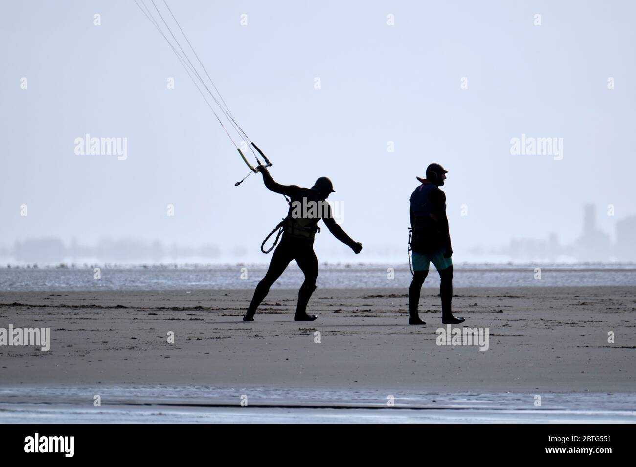 Silhouetten von Menschen mit Drachen am Strand gegen Himmel, Konzept von Abenteuersport und Freizeit Stockfoto