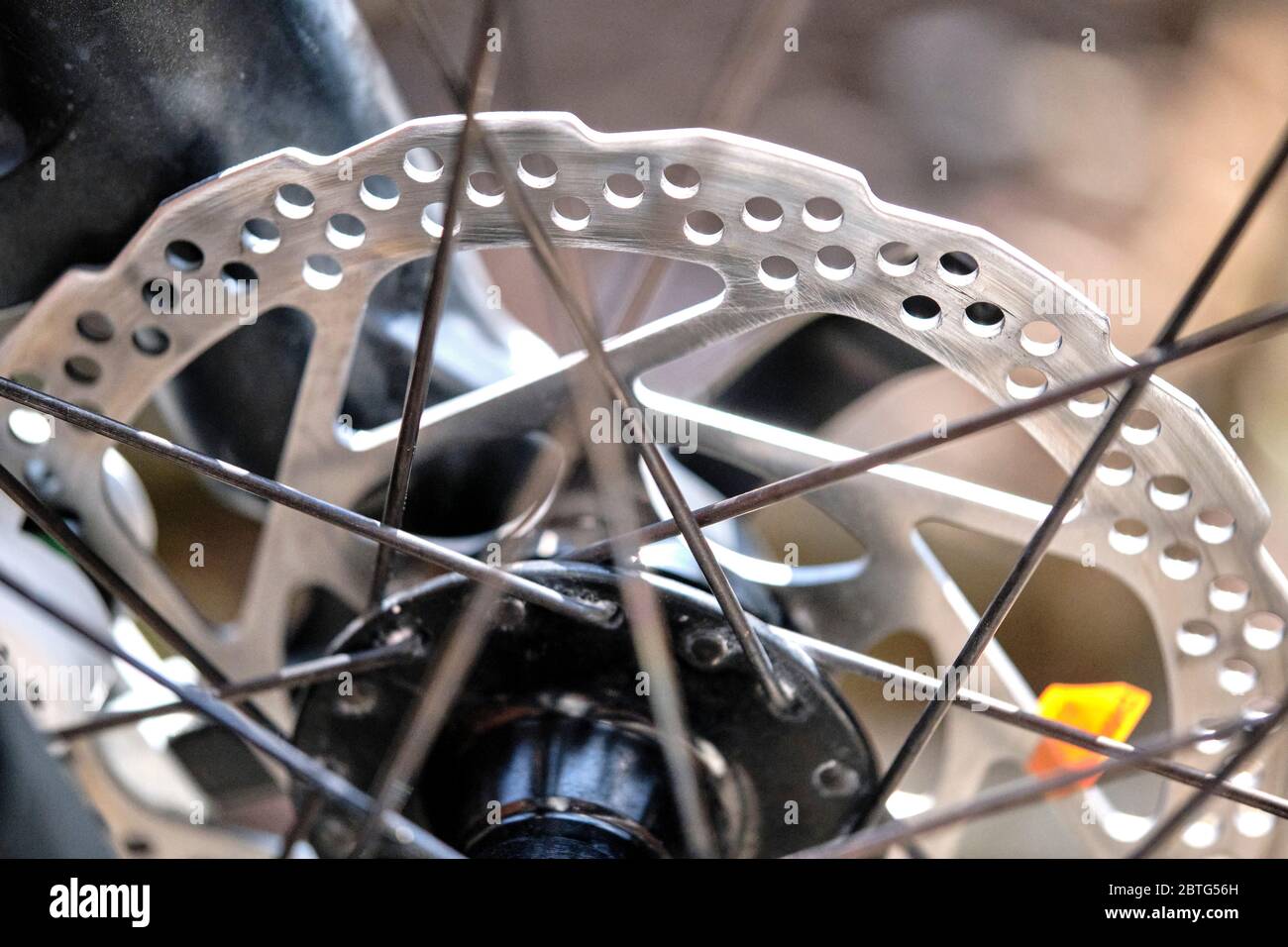 Nahaufnahme eines Radbremssystems mit Metallrotor, Bremssattel und Speichen auf verschwommenem Hintergrund Stockfoto