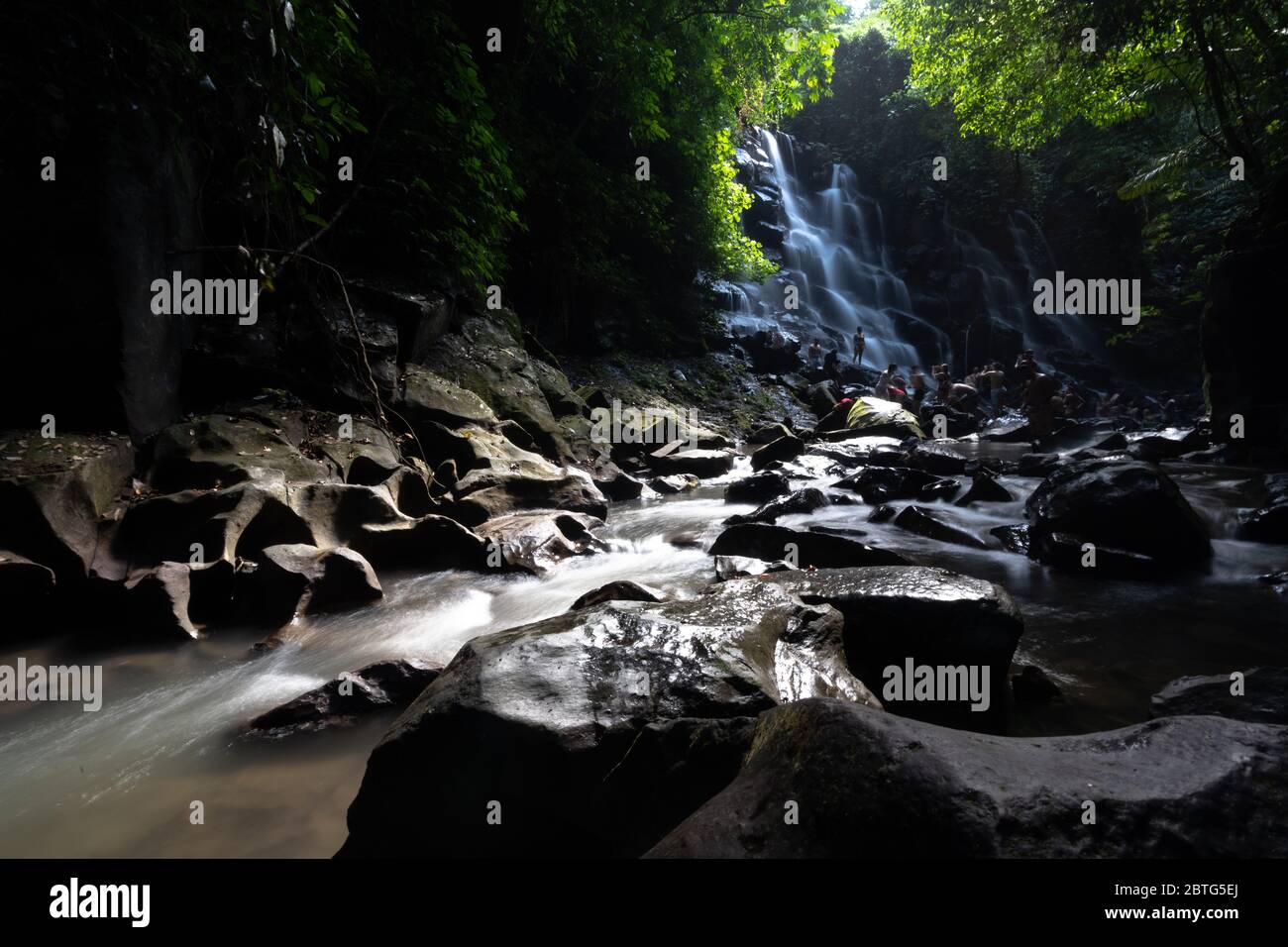 Wunderschöne Szene mit Wasserfall und Sonne, die durch die Bäume in bali indonesien scheint Stockfoto