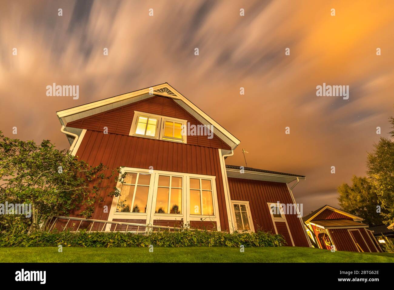 Lange Belichtung Nachtfoto von traditionellen roten Holz schwedischen Haus und dunklen schweren Wolken Stockfoto