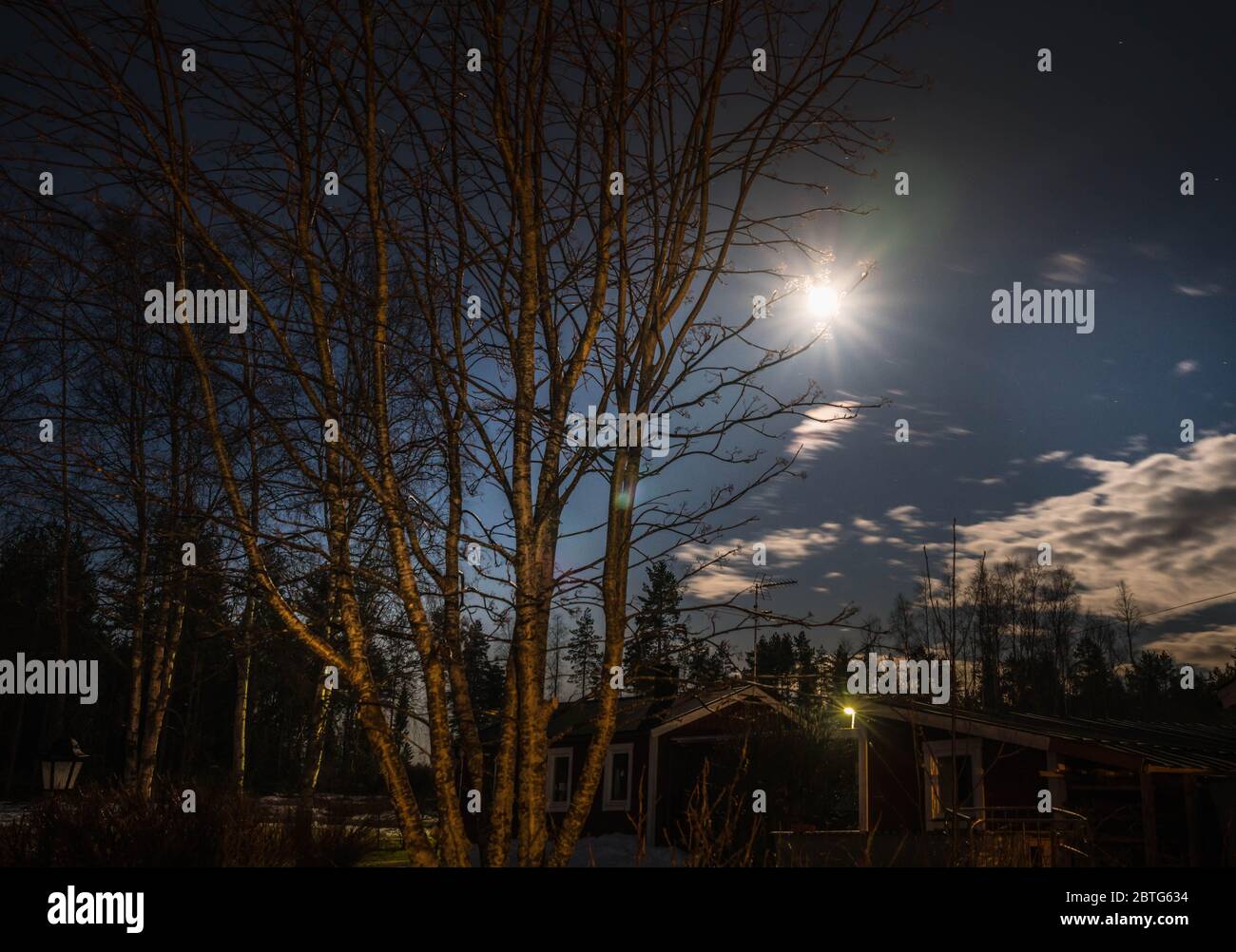 Schwedischer Garten bei Nacht, Vollmond neben Wolken, Frühling, etwas Winterschnee hier Stockfoto