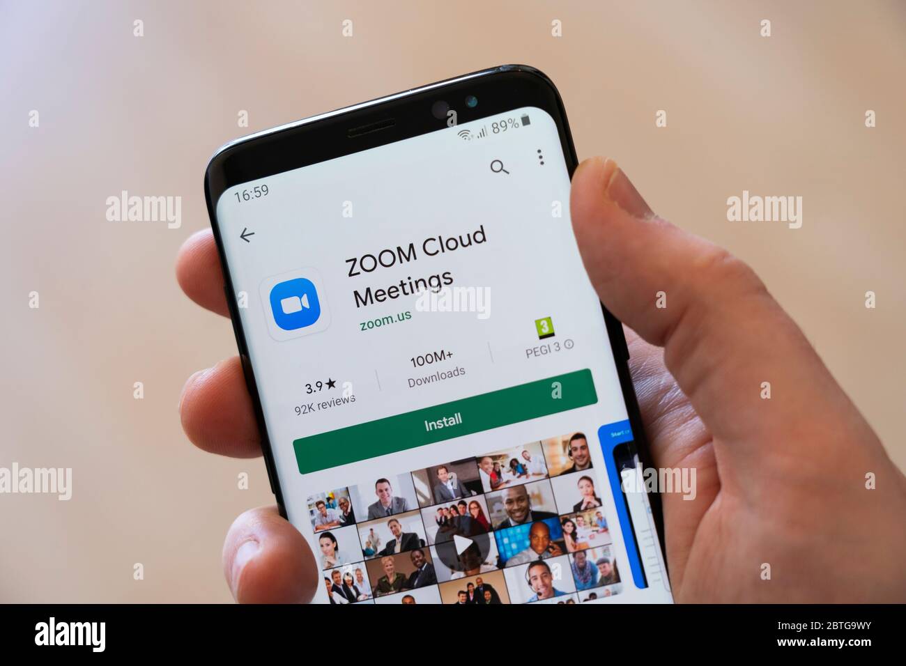 Ein Mann die Hand hält ein Smartphone zeigt die Google Play-Installationsbildschirm für die Video-Anruf Medien-App Zoom Cloud Meetings Stockfoto